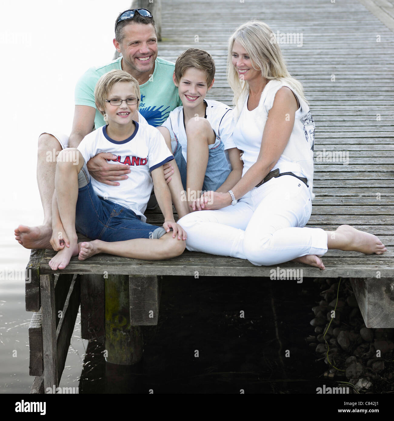 Familie zusammensitzen am dock Stockfoto