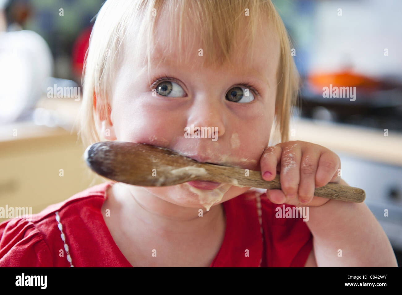 Kleinkind Mädchen lecken Holzlöffel Stockfoto