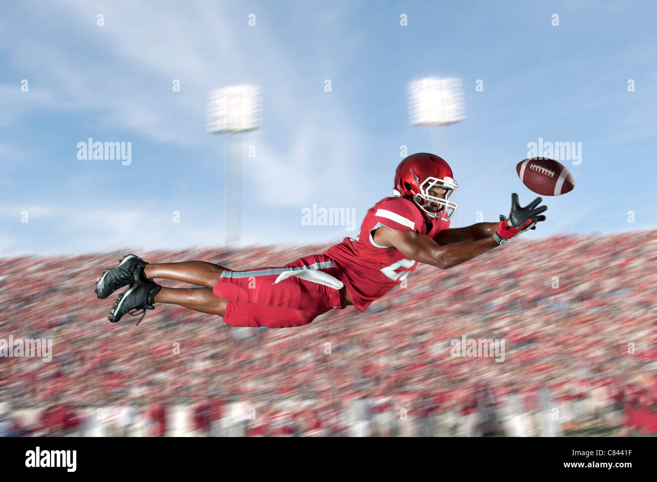 African American-Football-Spieler springen in der Luft fangen Fußball Stockfoto