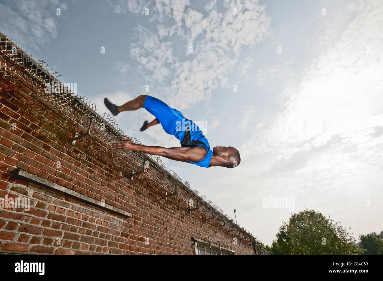 Athlet Voltigieren über Ziegelmauer Stockfoto