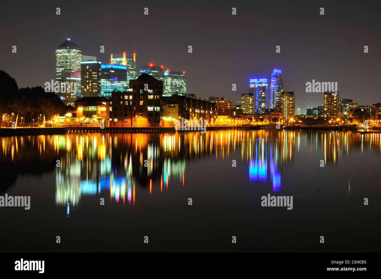 London Docklands Skyline bei Nacht, Richtung Canary Wharf aus Surrey Quays suchen, mit Spiegelungen im Wasser Stockfoto