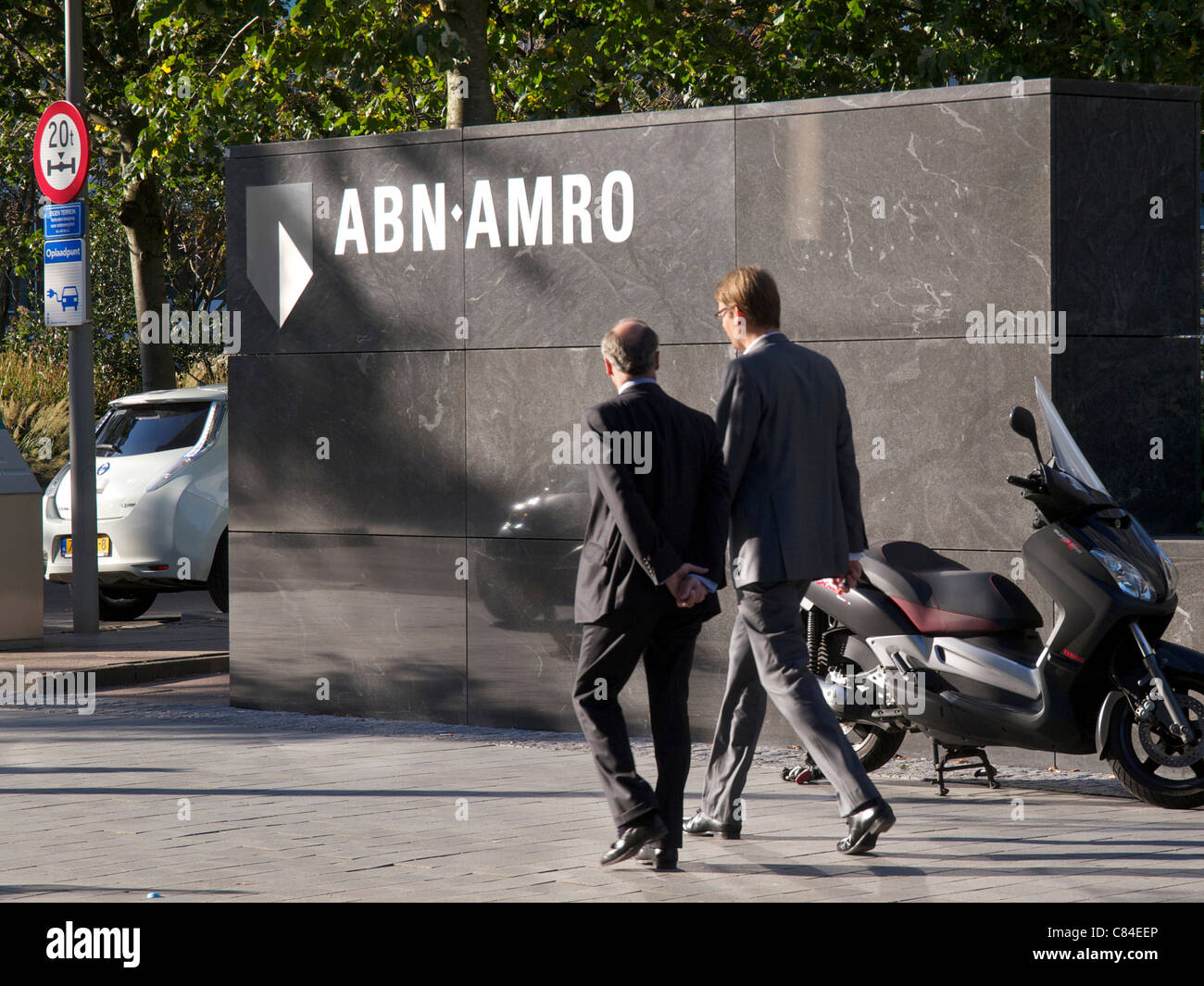 Logo mit zwei Männern zu Fuß vorbei an ABN Amro Bank Hauptsitz in Amsterdam, Niederlande. Stockfoto