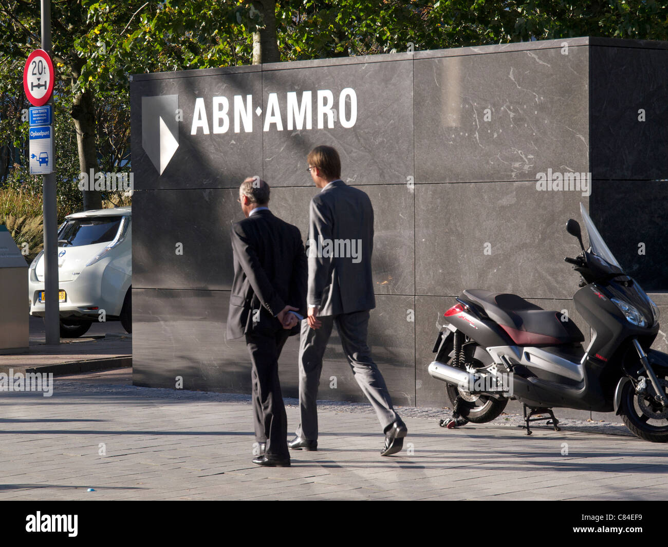 Logo mit zwei Männern zu Fuß vorbei an ABN Amro Bank Hauptsitz in Amsterdam, Niederlande. Stockfoto