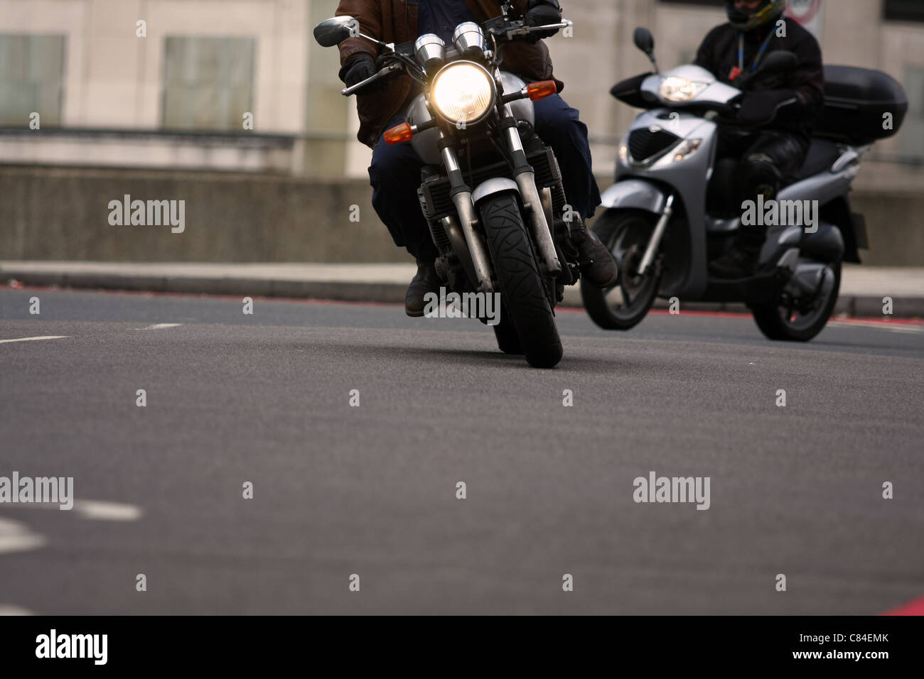 Teile von zwei Motorradfahrer unterwegs entlang einer Straße in London - eine auf einen Kreisverkehr und eine Eingabe des Kreisverkehrs Stockfoto