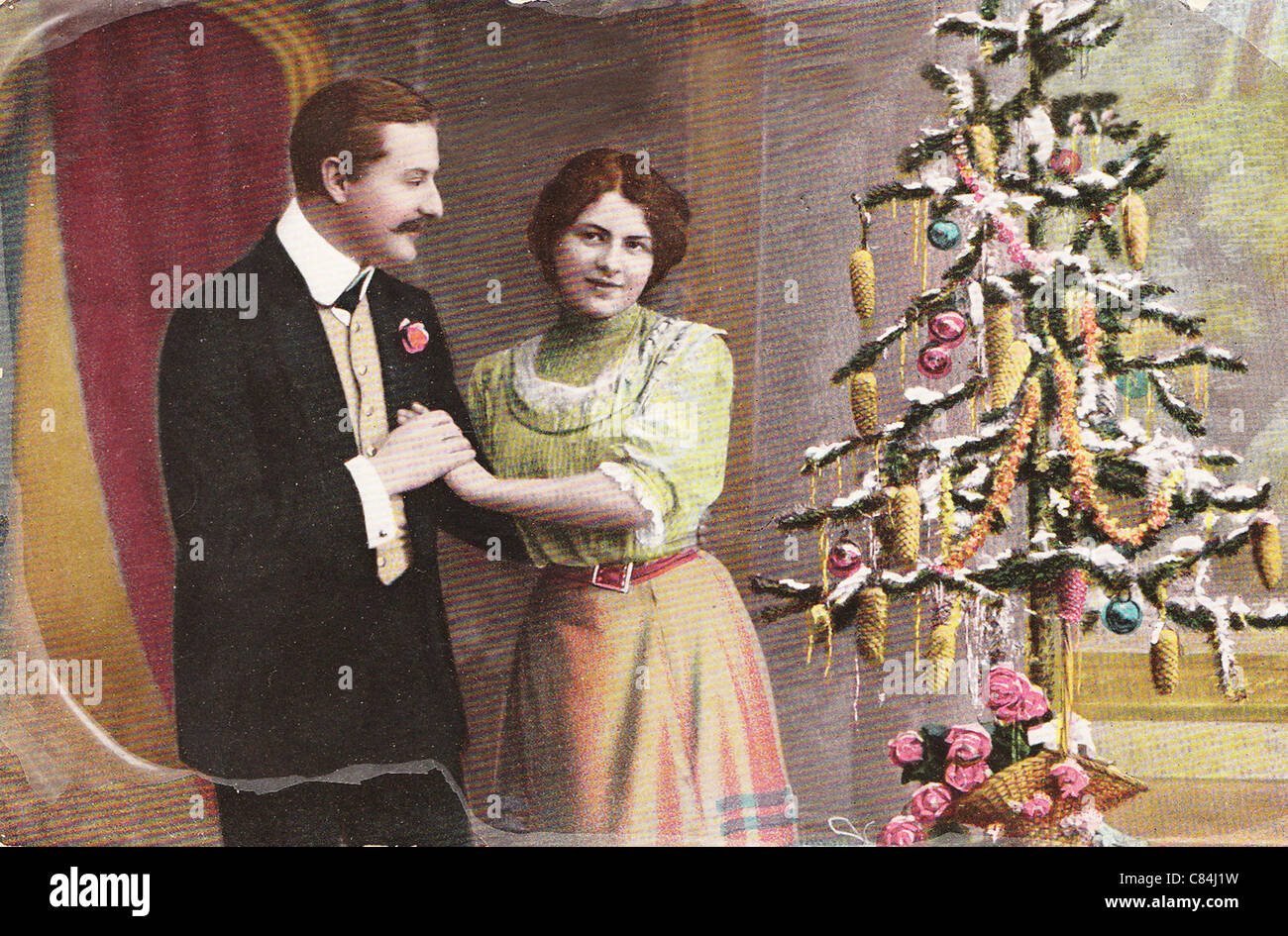 Vintage Weihnachtsgrußkarte von 1910 mit Liebespaar in der Nähe von Kleinbaum Stockfoto