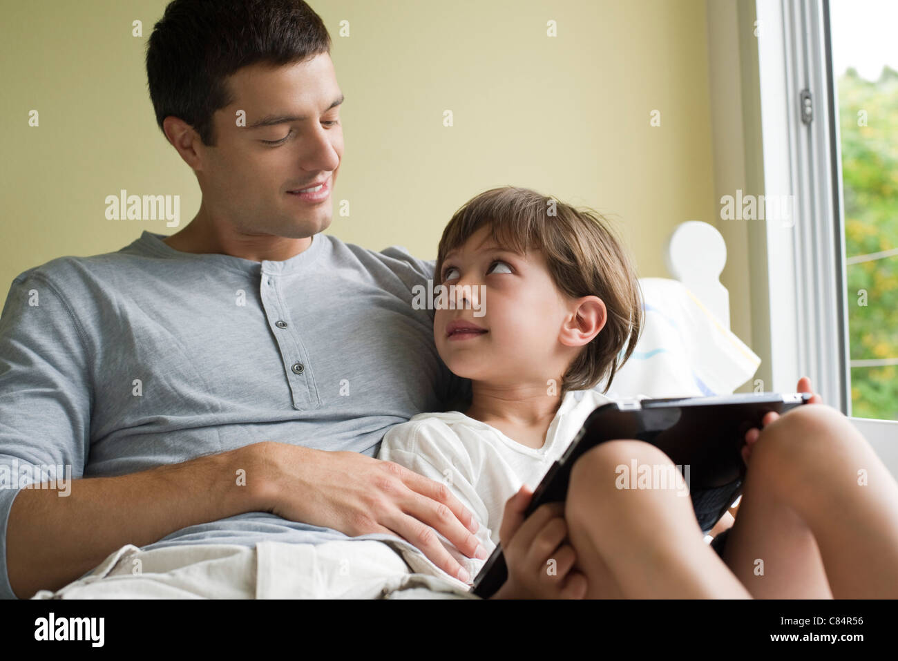 Vater und Sohn zusammen mit elektronischen Buch entspannende Stockfoto