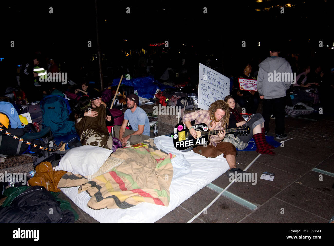 Occupy Wall Street Demonstranten in Zuccotti Park vorbereiten für die Nacht ins Bett nach unten wie ein Mann seine Gitarre spielt Stockfoto