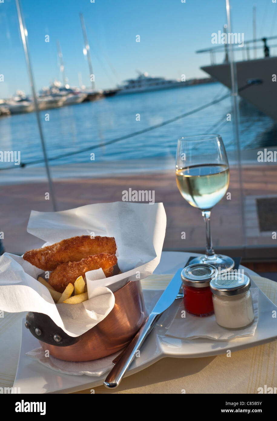 PUERTO PORTALS TAPAS Luxus Fisch & Chips Mahlzeit serviert am Wasser Marina Restaurant mit Blick auf den Yachthafen & Yachten im Hintergrund Palma de Mallorca Spanien Stockfoto