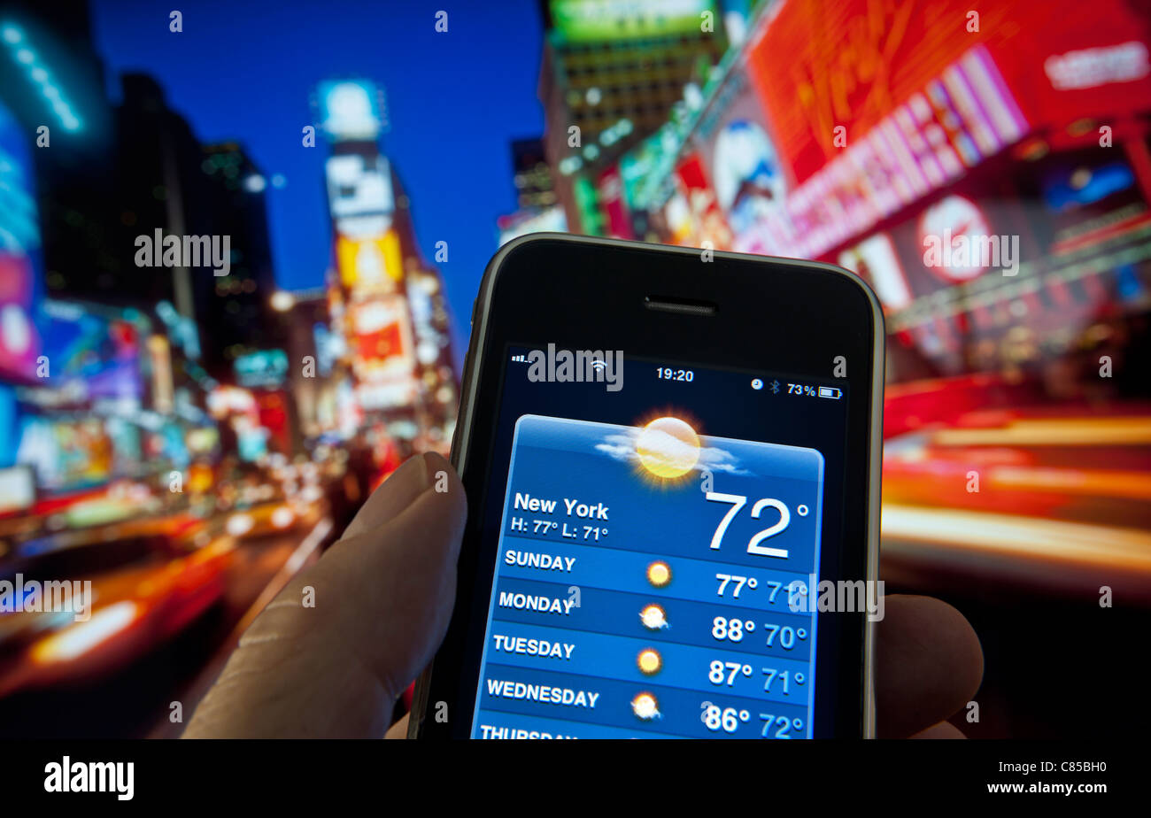 SMARTPHONE WETTER APP Times Square in der Dämmerung mit Hand, Apple iPhone, Bildschirm, der in der Woche vom 72 W Sun auf Wetter 4g Smartphone Anwendung Stockfoto
