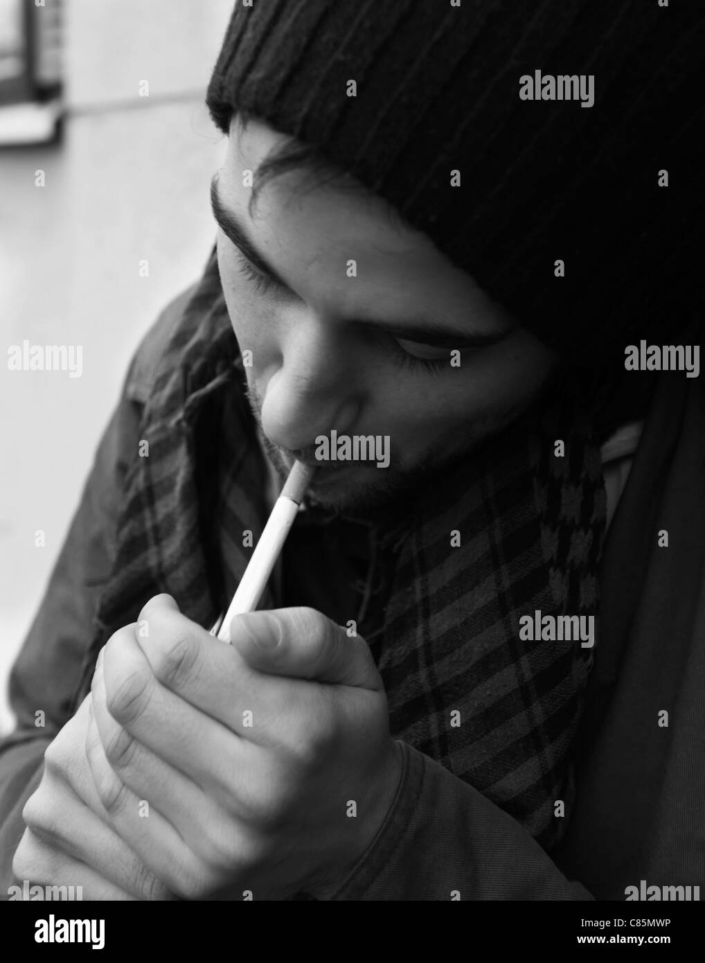 Ein junger Mann eine Zigarette außerhalb seiner Wohnung aufleuchten Stockfoto