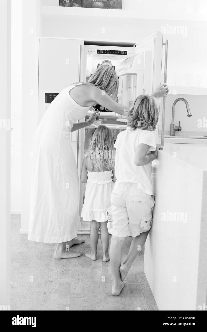 Mama helfen, Kinder Essen aus dem Kühlschrank zu bekommen Stockfoto