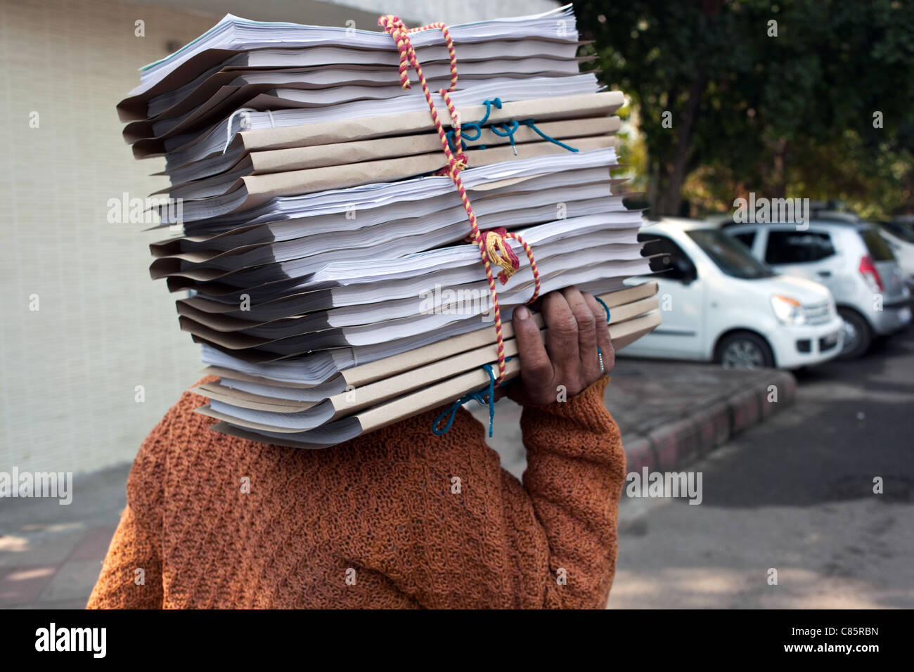 Ein Mann trägt einen Stapel von Dokumenten außerhalb eines der Gerichte in New Delhi, Indien. Stockfoto