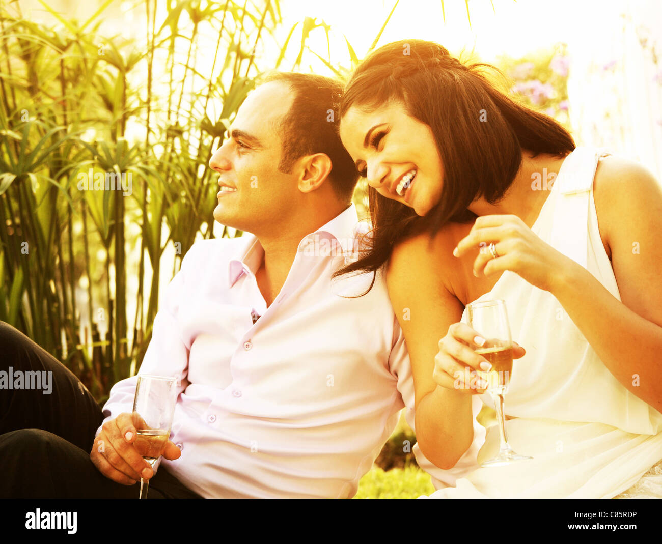 Glückliches junges Paar trinken Champagner im Freien, lachen und genießen Hochzeitstag Stockfoto