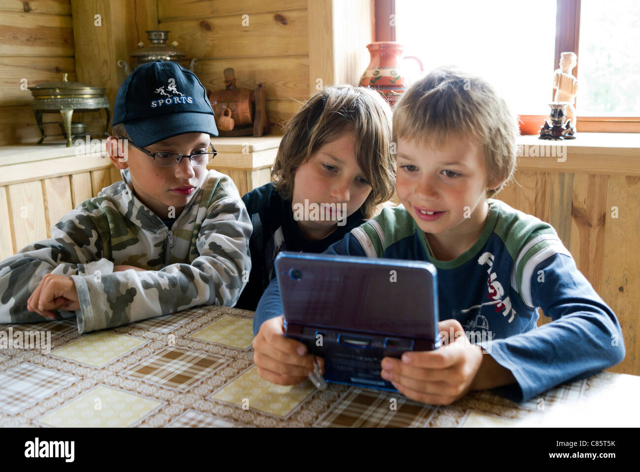 Polen, Biebrza River National Park, The Mammoth Valley (Mamucia Dolina), drei kleine Jungen genießen DS Nintendo-Konsolen-Spiele Stockfoto