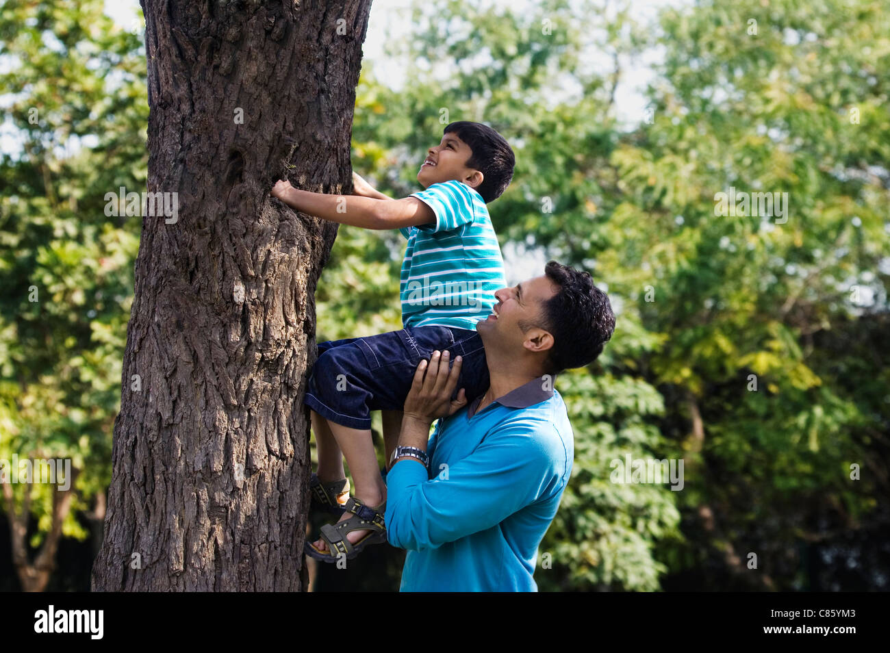 Vater seinen Sohn, einen Baum zu klettern zu helfen Stockfoto