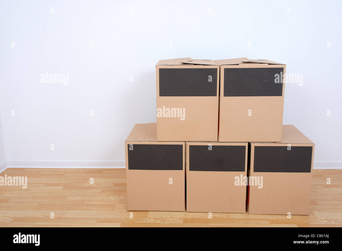 Foto von fünf Umzugskartons. Holzboden und weiße Wand Hintergrund. Stockfoto