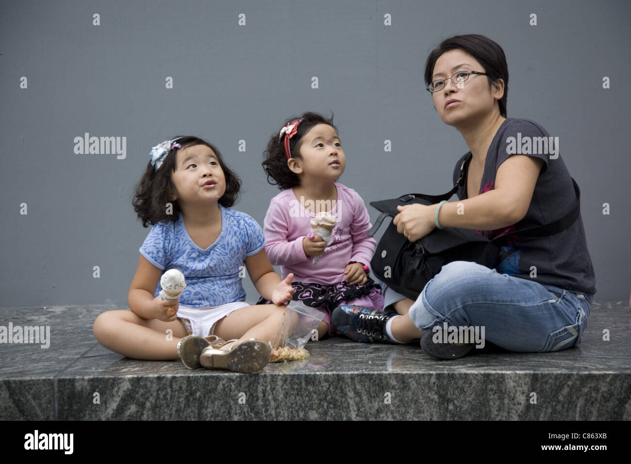 Mutter mit zwei jungen Mädchen essen Eis Kegel Blick bis auf die hohen Gebäude in Manhattan. Stockfoto