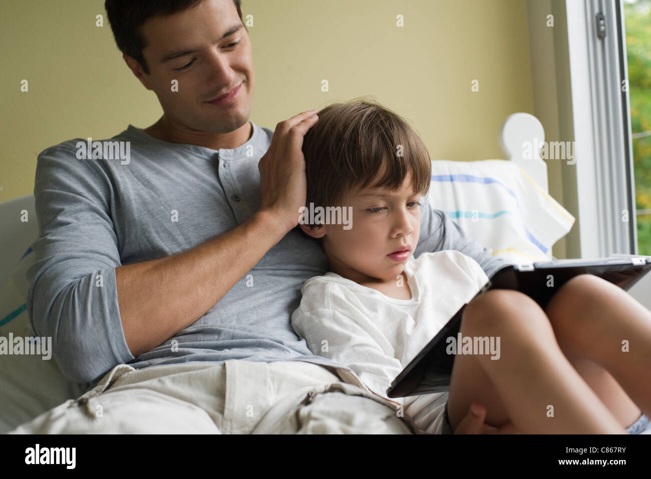 Vater und Sohn zusammen mit elektronischen Buch entspannende Stockfoto
