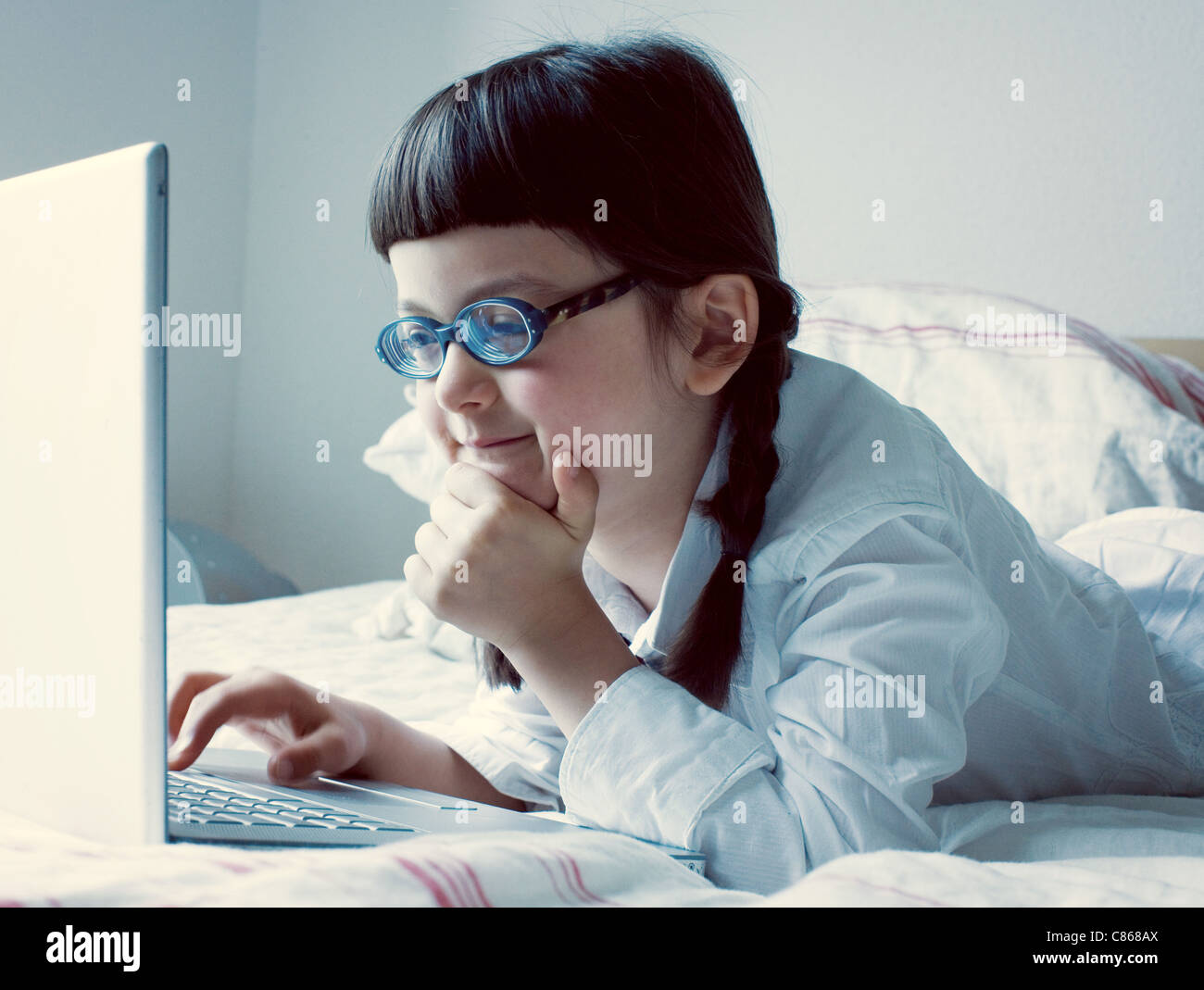 Mädchen auf Bett mit Laptop-computer Stockfoto