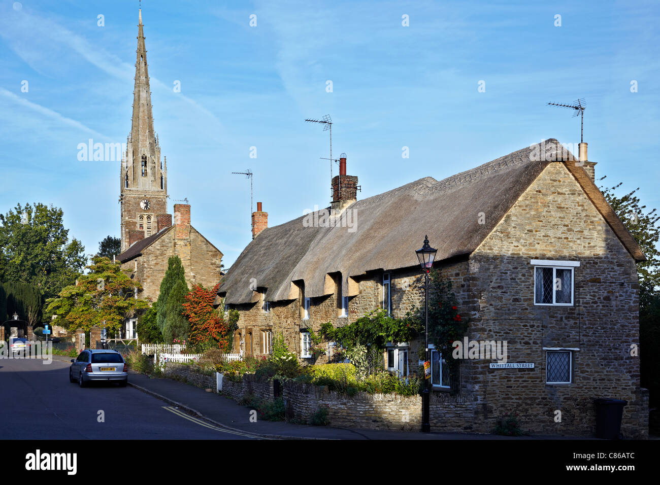Dorfkirche Großbritannien. Kings Sutton Pfarrkirche und strohgedeckte Hütten Oxfordshire England Großbritannien Stockfoto