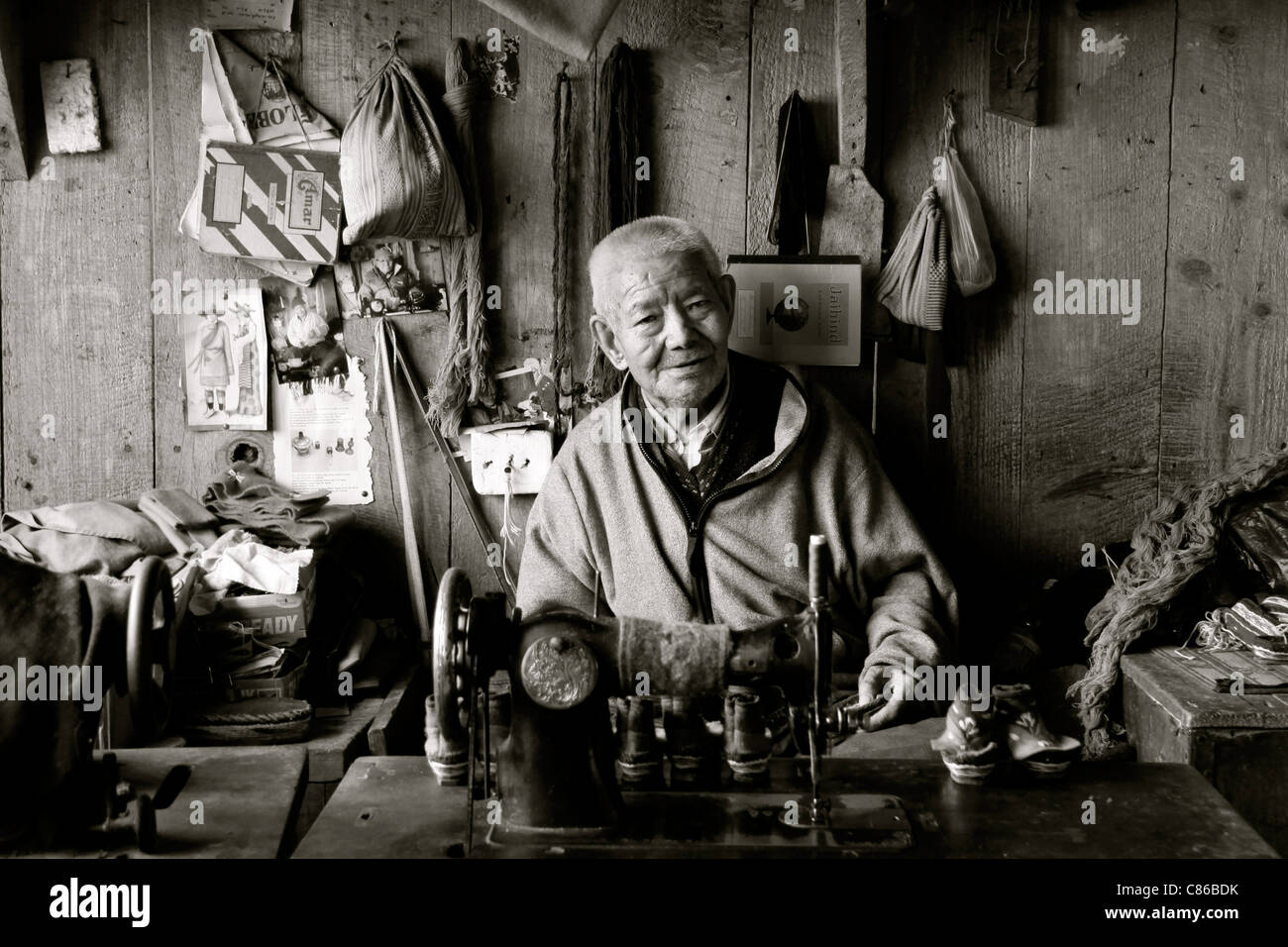 Ein buddhistischer Mönch zu arbeiten um Kleidung in einem tibetischen Flüchtlings-Zentrum in der Nähe von Darjeeling, Indien Stockfoto