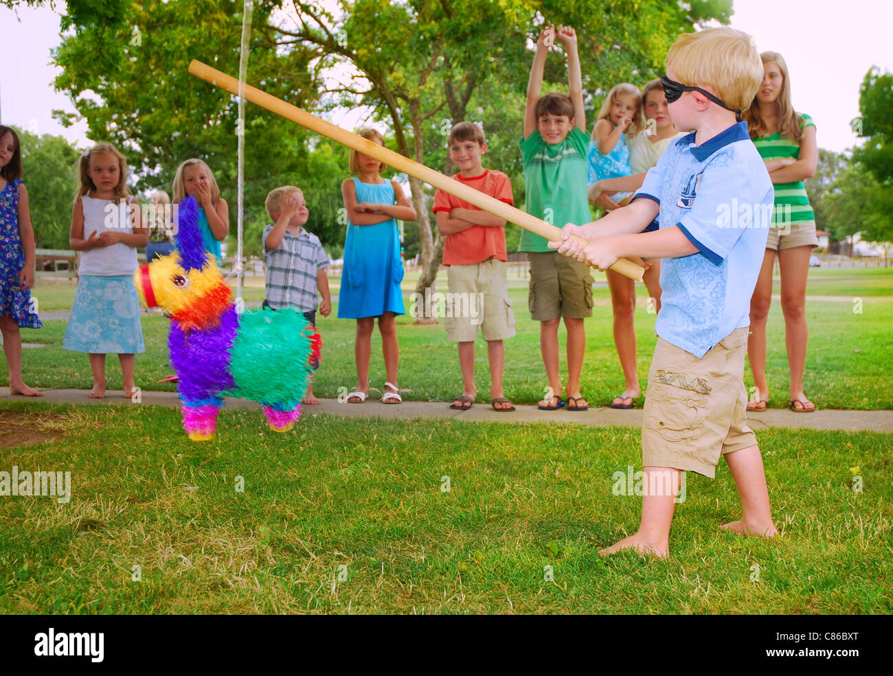 Junge schwingt einen Stick an ein Pinata auf Kinder Geburtstagsparty Stockfoto
