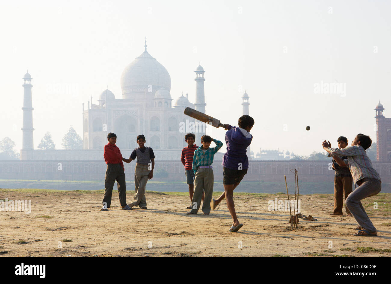 TAJ MAHAL: JUNGS SPIELEN CRICKET ON YAMUNA RIVER BANK Stockfoto