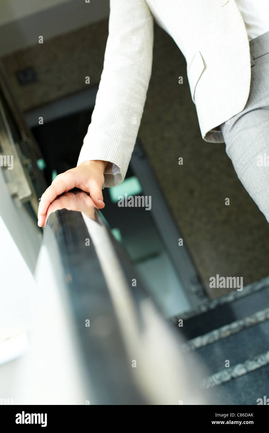 Bild von weiblicher Hand, die Geländer beim Abstieg im Bürogebäude Stockfoto
