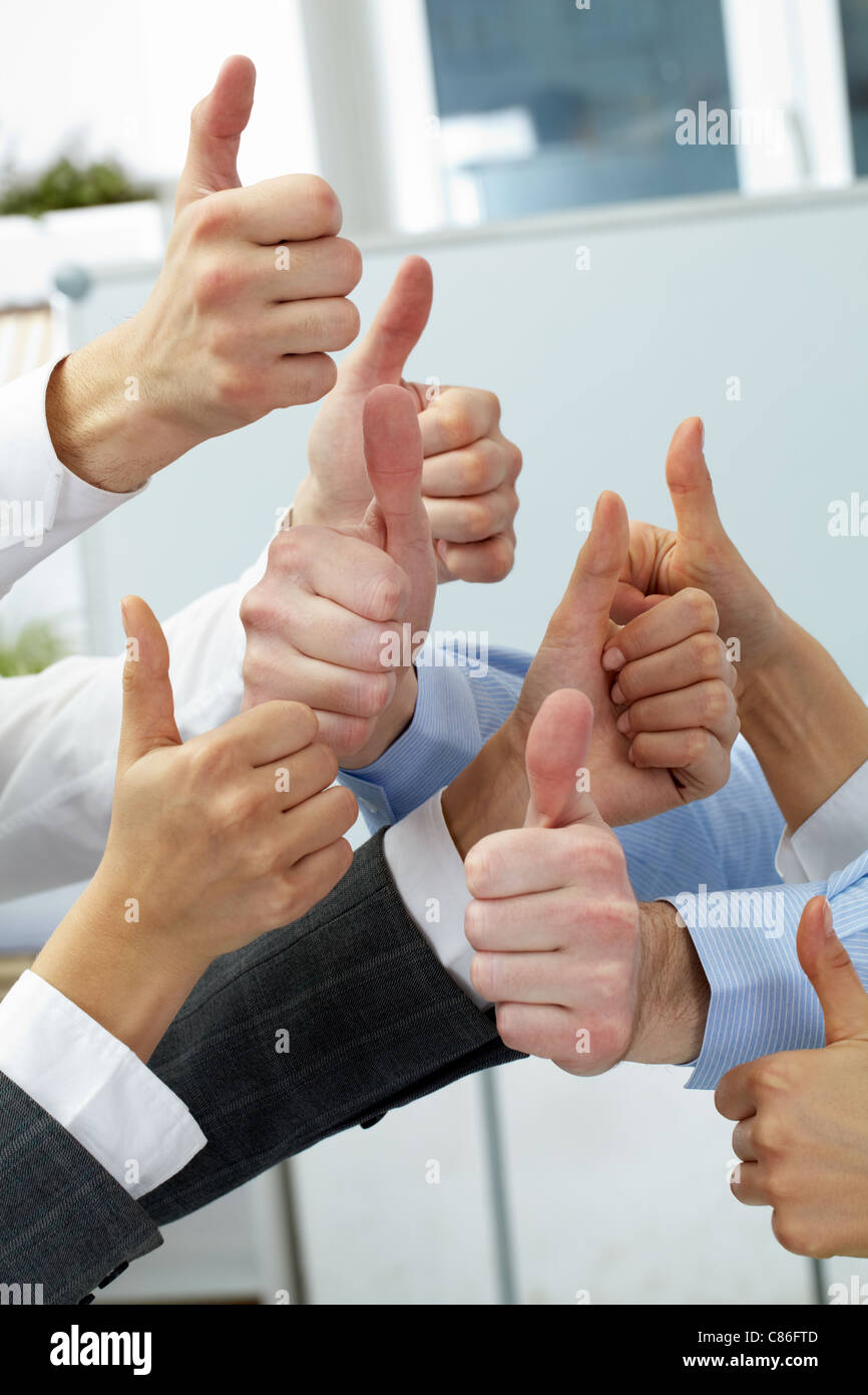 Hände von vier Geschäftsleuten, die Daumen zeigen Stockfoto