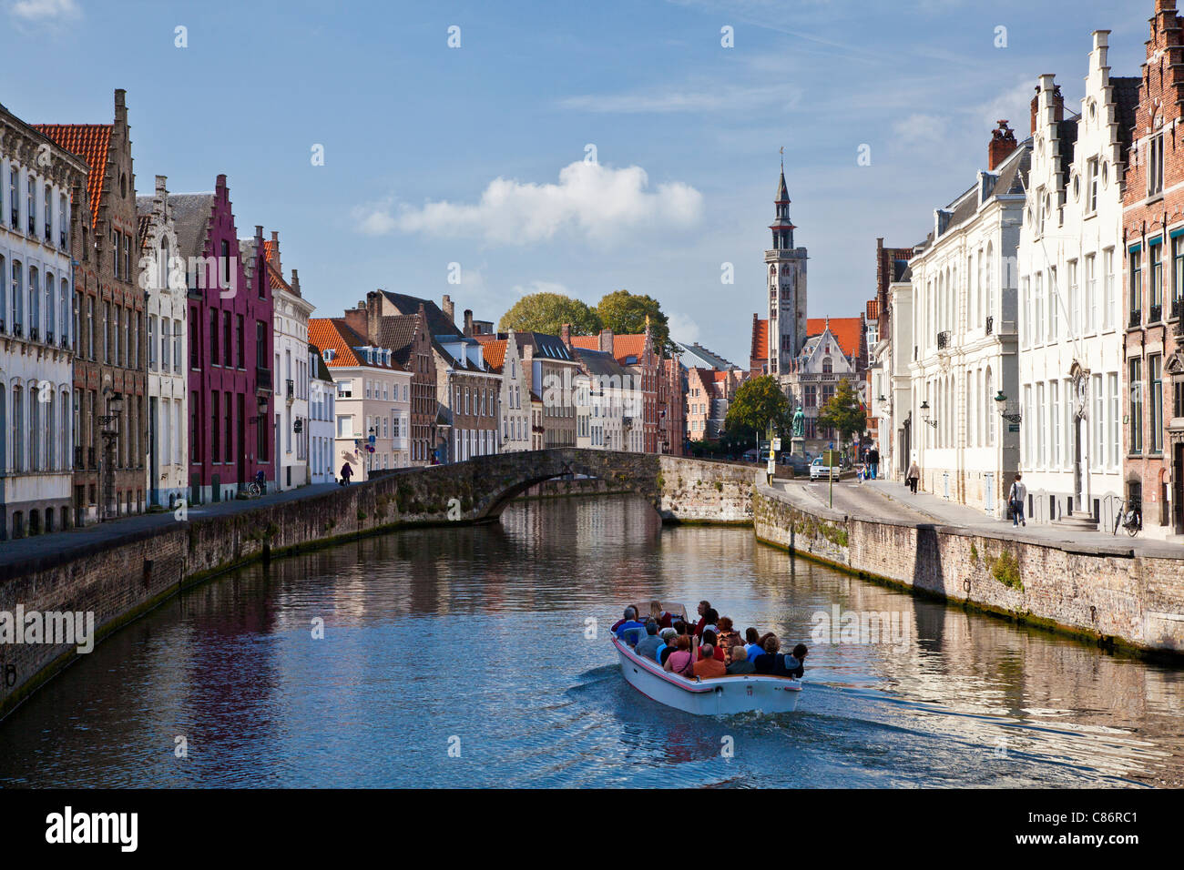 Touristenboot auf dem Kanal entlang der Spinolarei und Spiegelrei in Bruges,(Brugge), Belgien mit der Poortersloge in der Ferne. Stockfoto