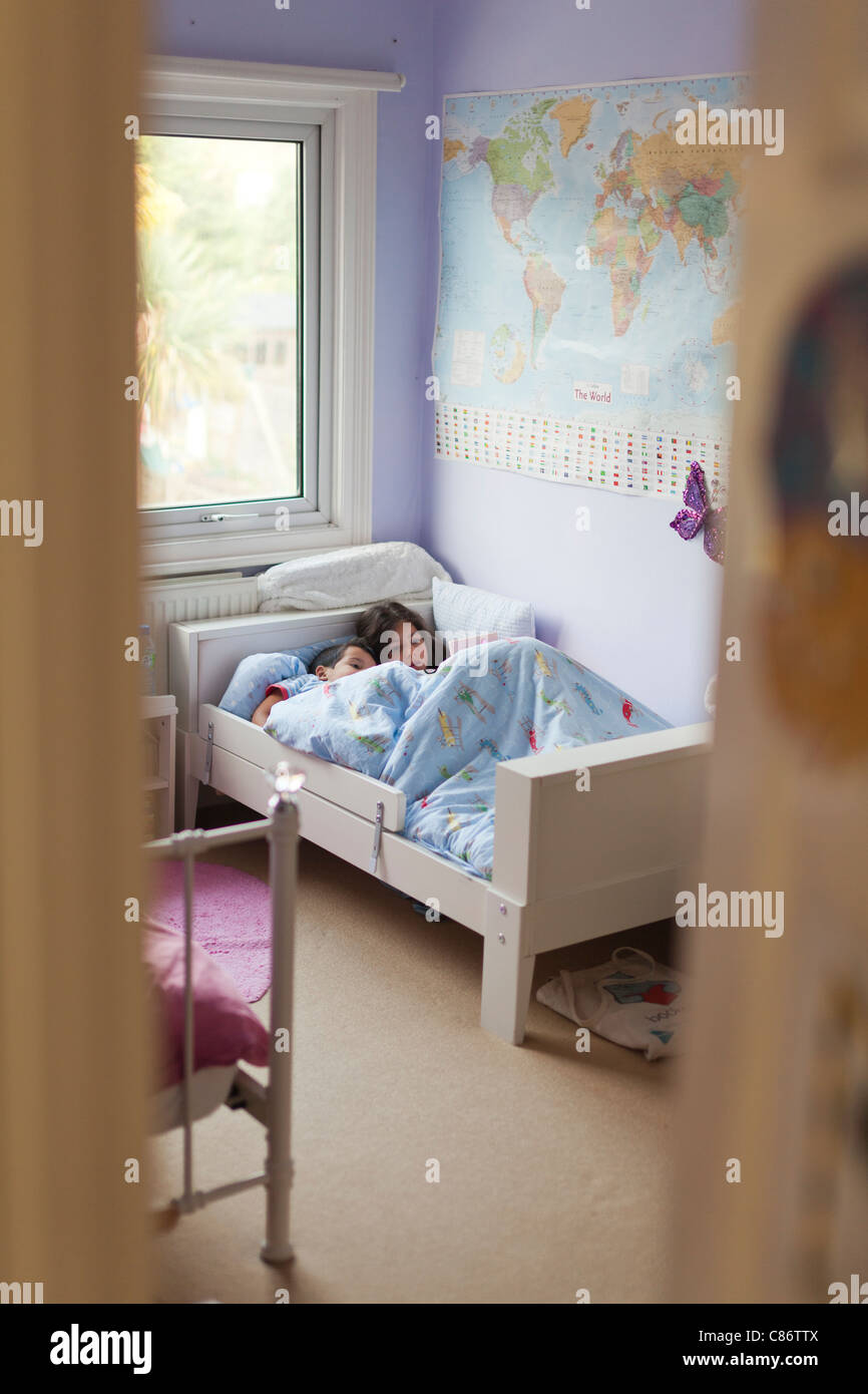 Kinder spielen auf dem Nintendo DS im Bett aus der Ferne Stockfoto