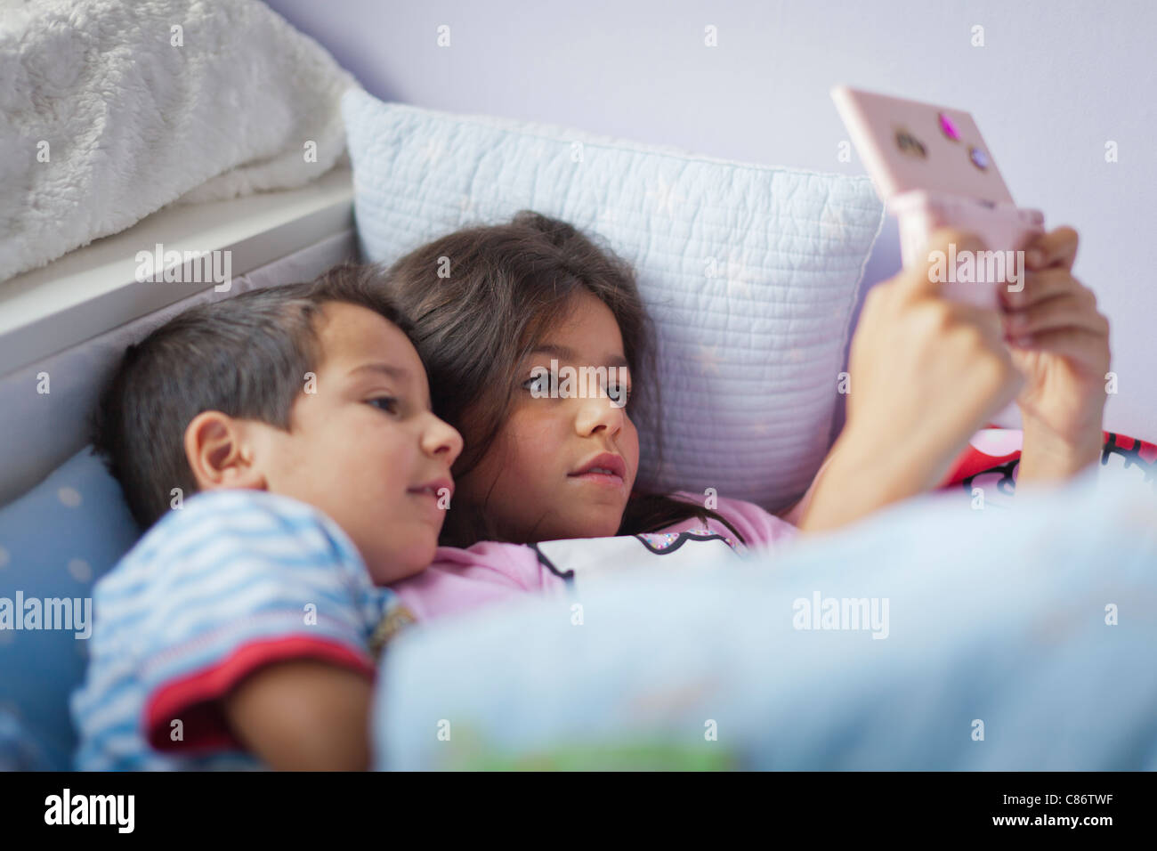 Kinder spielen auf dem Nintendo DS im Bett Stockfoto