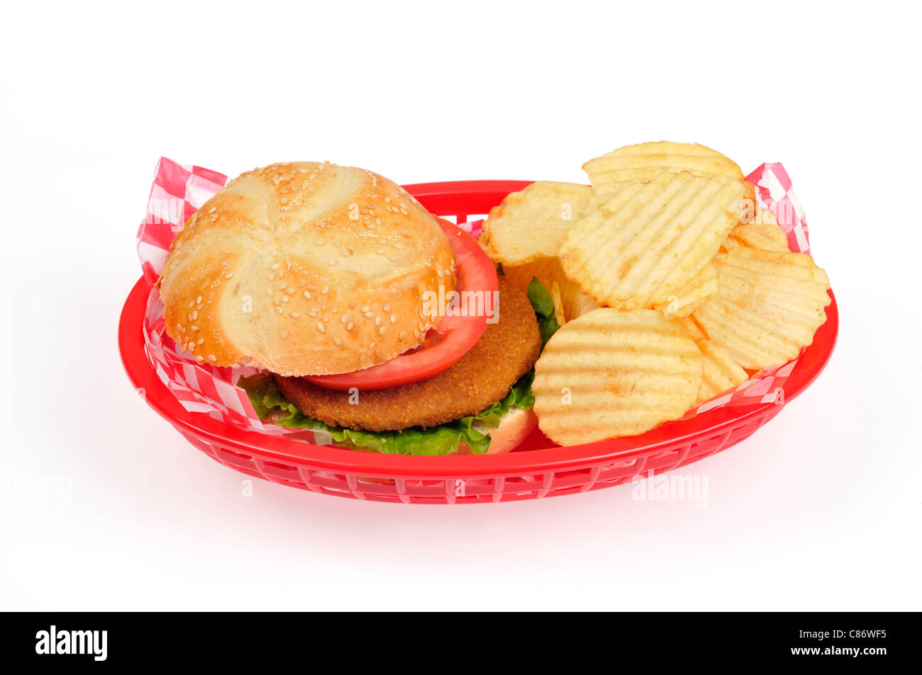Patty Chicken Burger mit Salat und Tomaten in einer Rolle mit Chips in einer retro Kunststoff Warenkorb Stockfoto