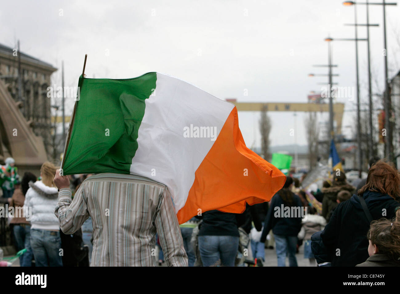 Familie tragen irische Trikolore in Richtung Harland und Wolff Werft Krane, Symbol der Gewerkschaftsbewegung bei St Patricks Day Parade am St. Patricks Day Feierlichkeiten, Belfast City Centre. Stockfoto