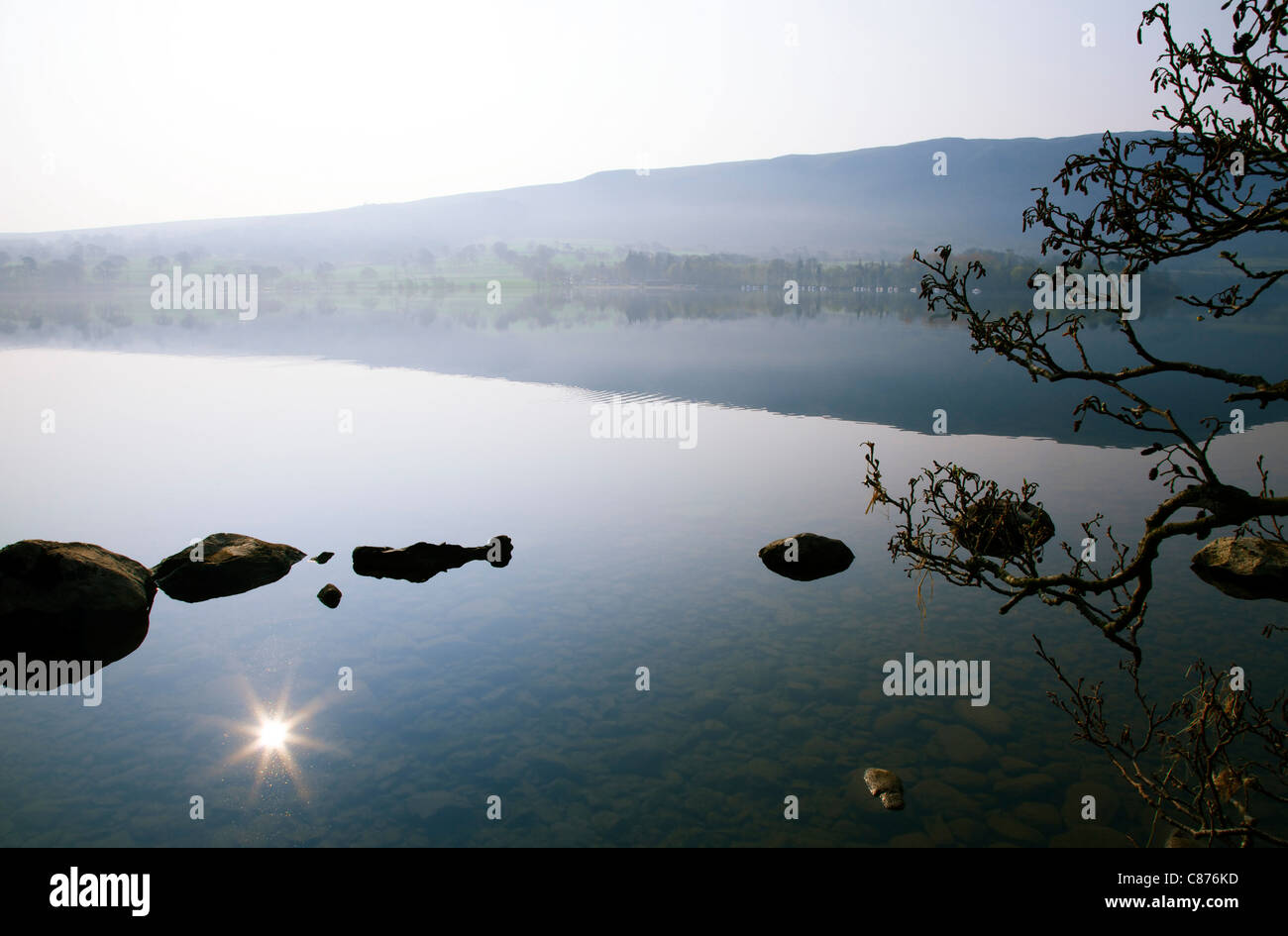 Ullswater-See in der Morgendämmerung mit leichter Nebel und Streulicht auf die Reflexion der Sonne im Wasser Stockfoto