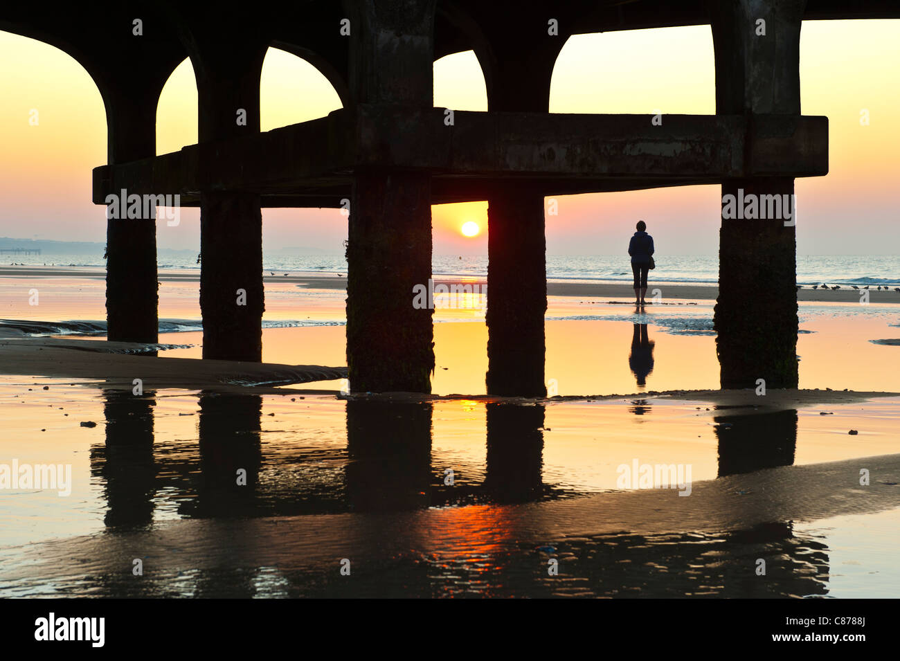 Frau alleine am Strand von Bournemouth bei Sonnenaufgang Stockfoto