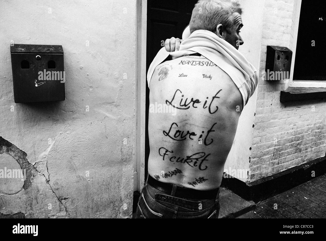 Tätowierte Mann vor Pub mit Aufschrift "Live it, Love it, Fcuk es ', B&W Straße gedreht un gestellt Stockfoto
