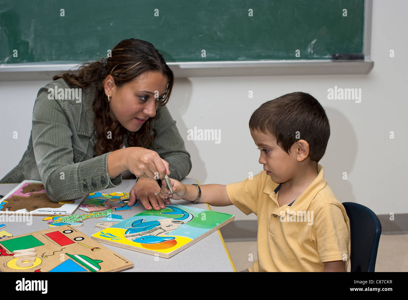 Vorschullehrerin helfen 4 jährige kaukasische junge Schüler im Klassenzimmer eine Puzzle zusammengestellt Stockfoto