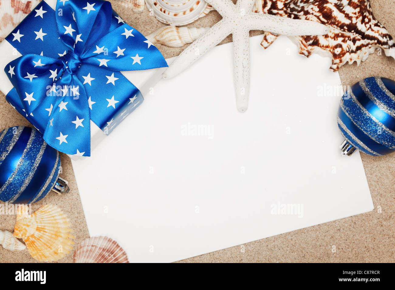 Weihnachtsgeschenke und leere Karte am Sandstrand, Nahaufnahme. Stockfoto