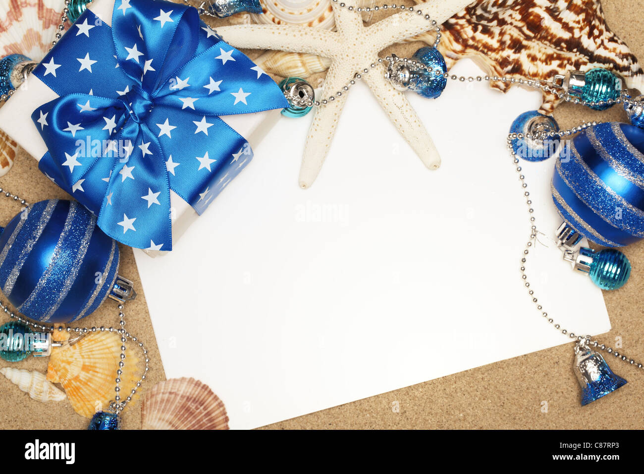 Weihnachtsgeschenke und leere Karte am Sandstrand, Nahaufnahme. Stockfoto