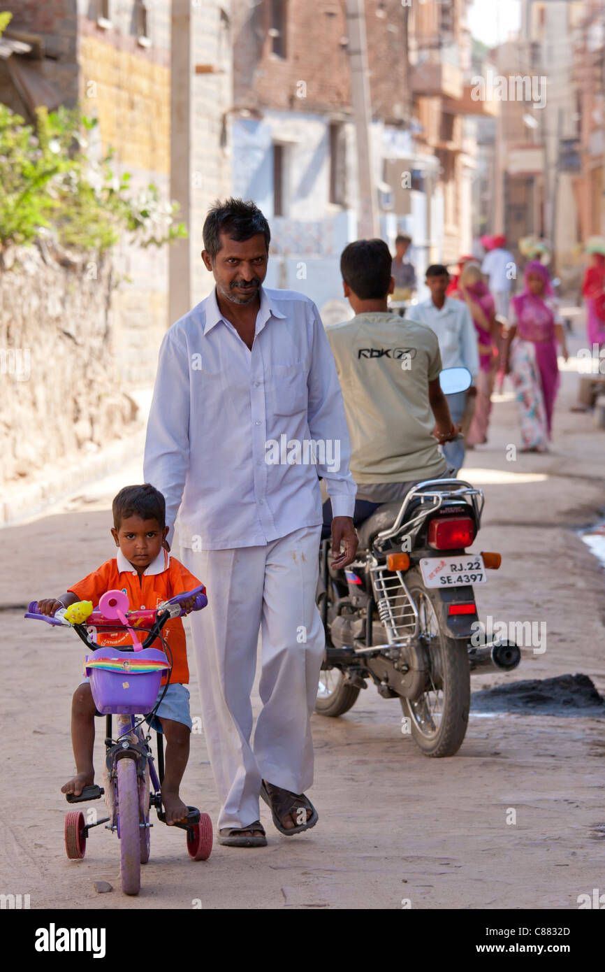 Indischer Mann mit Kind auf dem Dreirad in das Dorf Narlai in Rajasthan, Nordindien Stockfoto