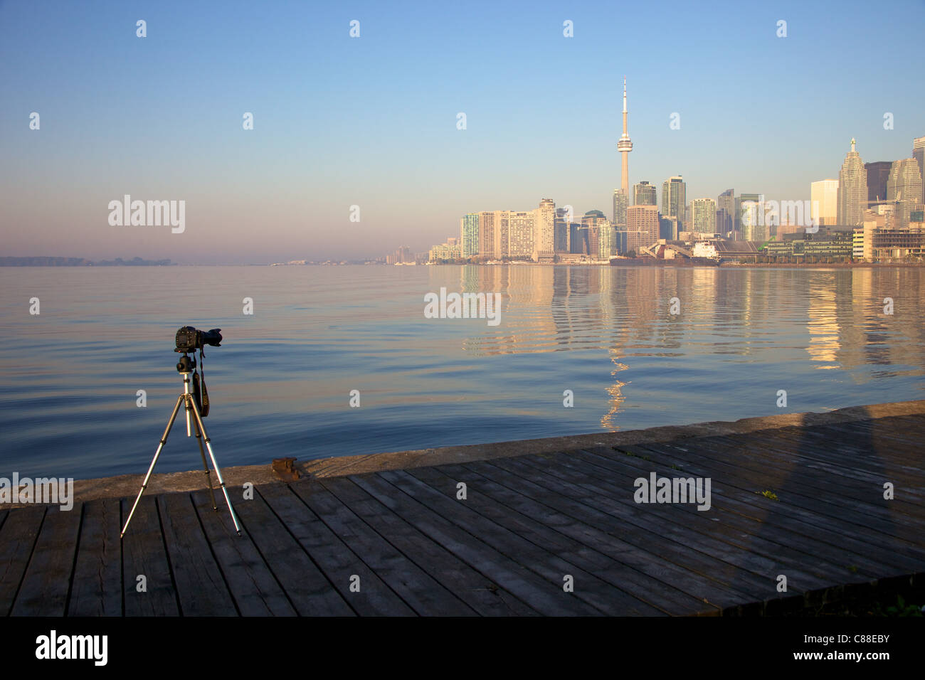 Eine einsame Kamera auf einem Stativ wartet auf Sonnenaufgang über See Ontario wies auf Toronto Stockfoto