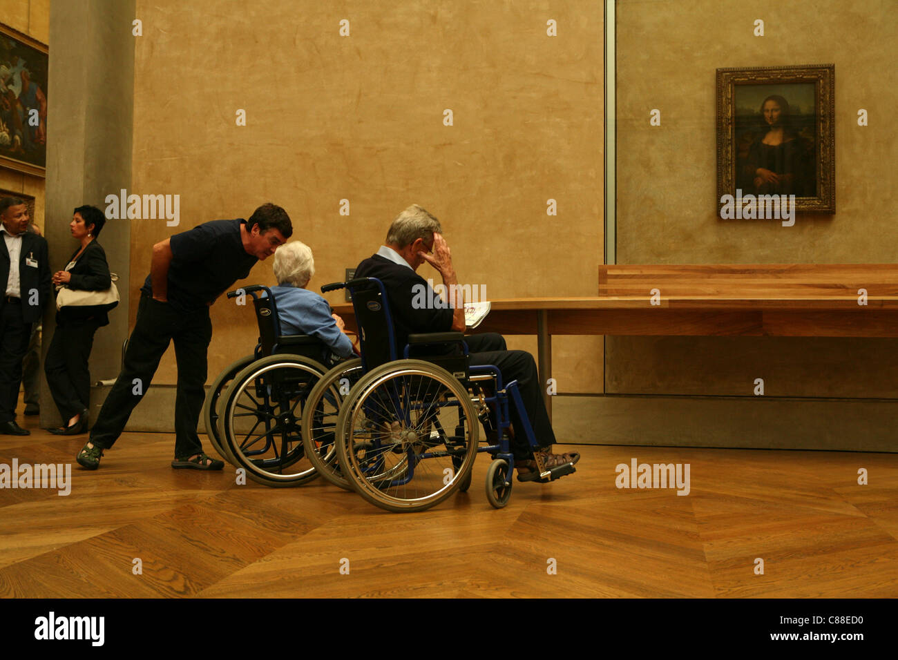 Behinderte Besucher im Rollstuhl geniessen das Porträt der Mona Lisa von Leonardo da Vinci im Louvre in Paris, Frankreich. Stockfoto