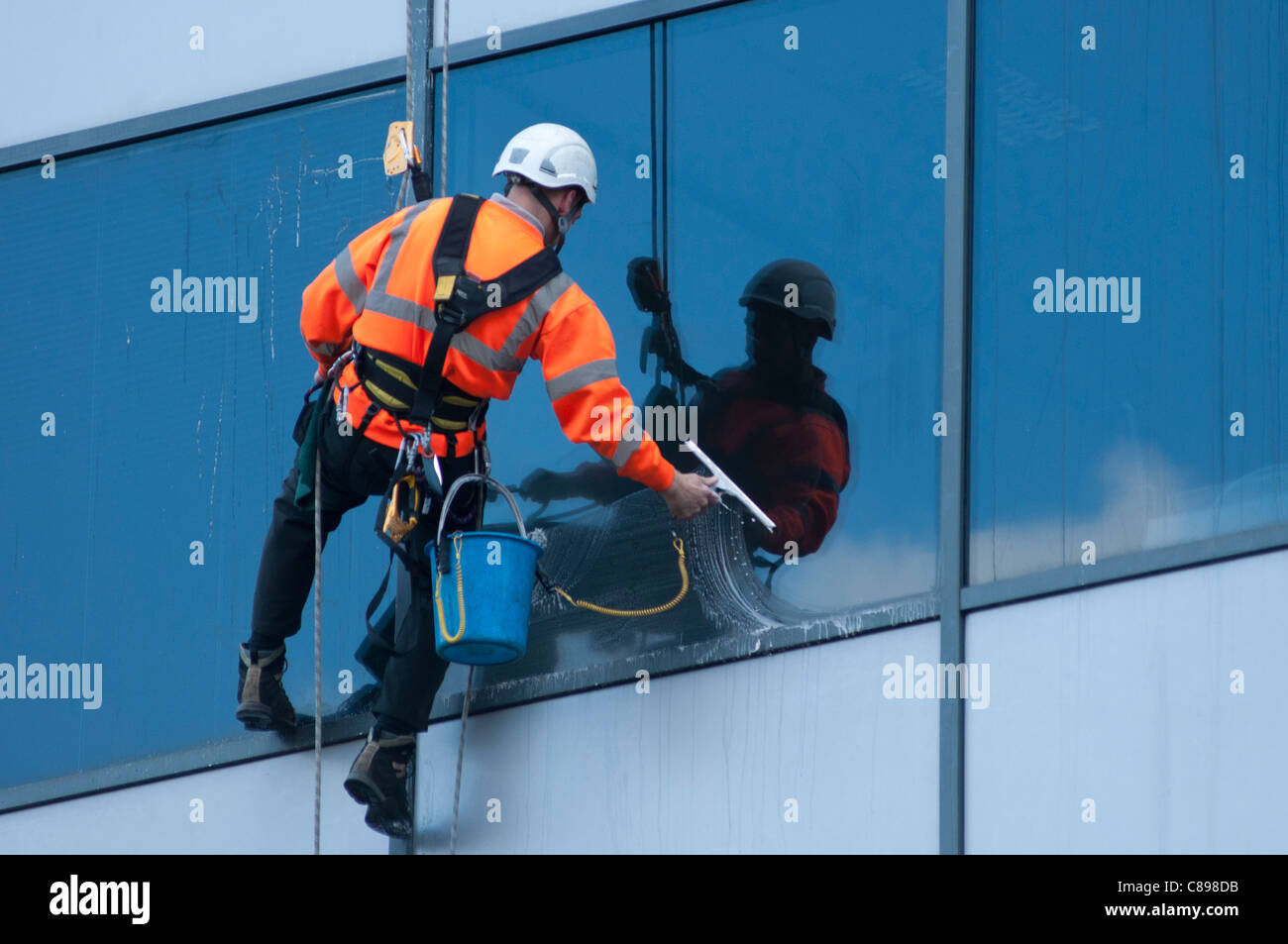 Ein Fensterputzer bei der Arbeit auf ein Bürogebäude in Birmingham, UK. Stockfoto