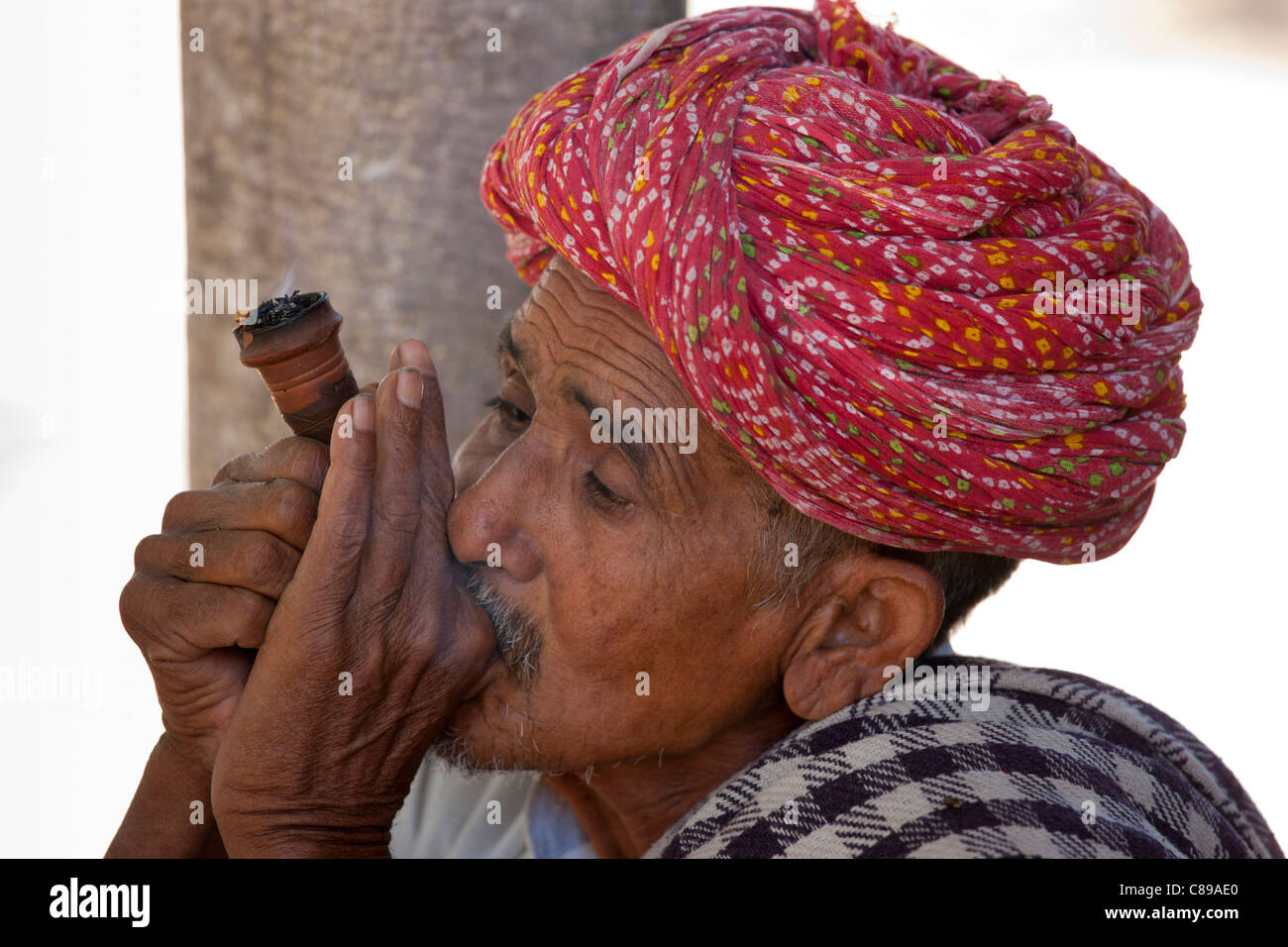 Indische Männer, ein Rauchtabak aus Chillam Ton-Rohr ist in Rajasthani Turbane in Nimaj Dorf, Rajasthan, Nordindien Stockfoto