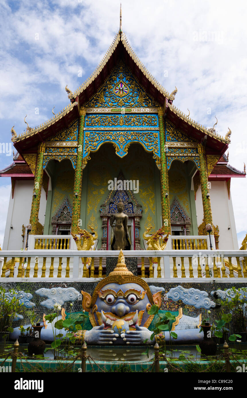 Große bunte Statue der buddhistischen Gottheit Kala mit weit aufgerissenen Augen vor reich verzierten Tempel im Norden Thailands Stockfoto