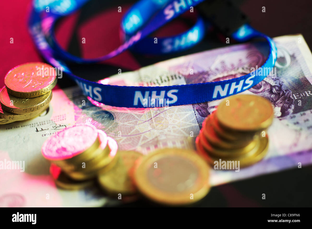 NHS Personal Hals Kette auflegen zwanzig Pfund-Noten umgeben mit Pfund-Münzen Stockfoto