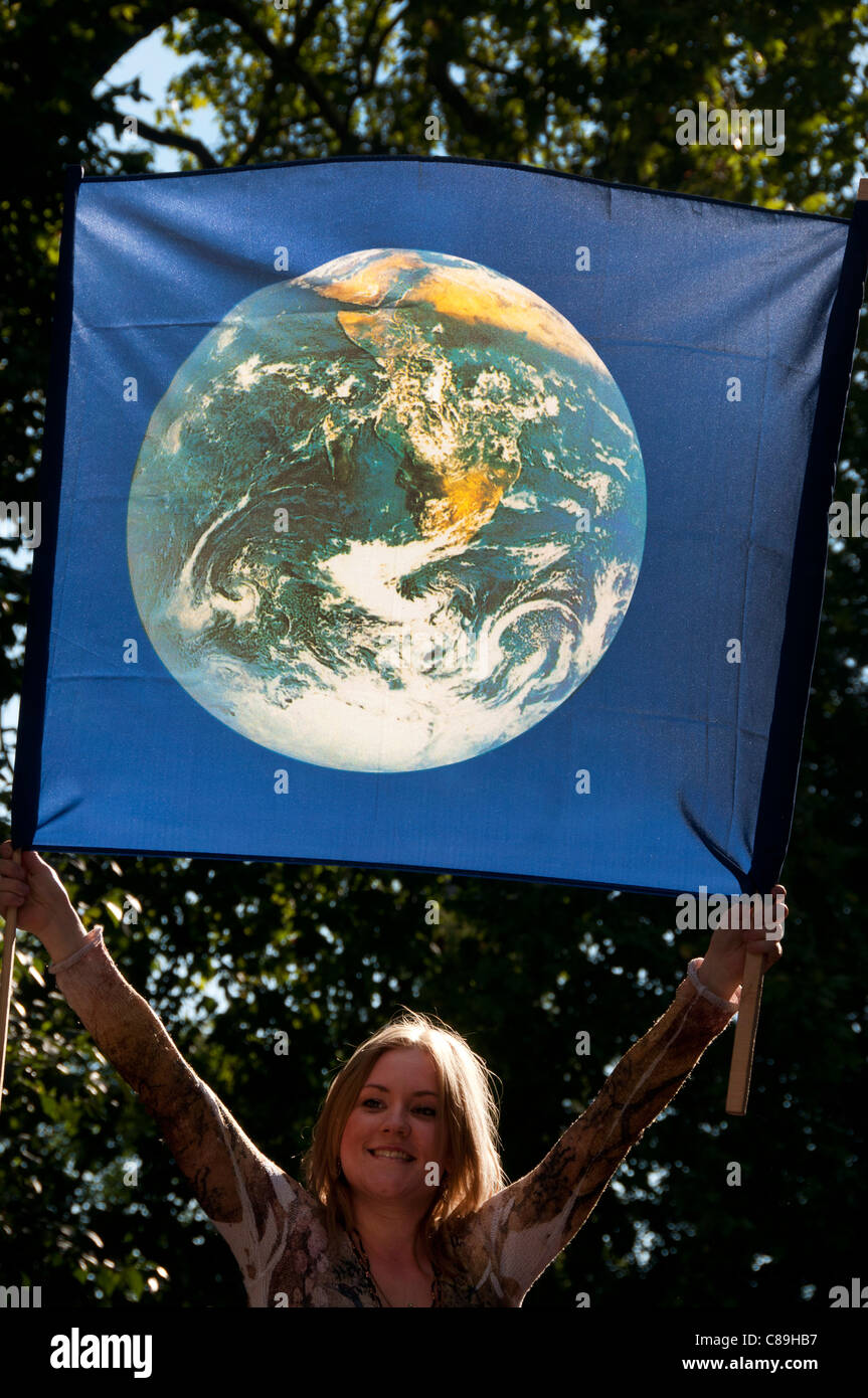 London.A Frau hält eine Fahne mit einem Bild der Erde darauf zu besetzen Stockfoto
