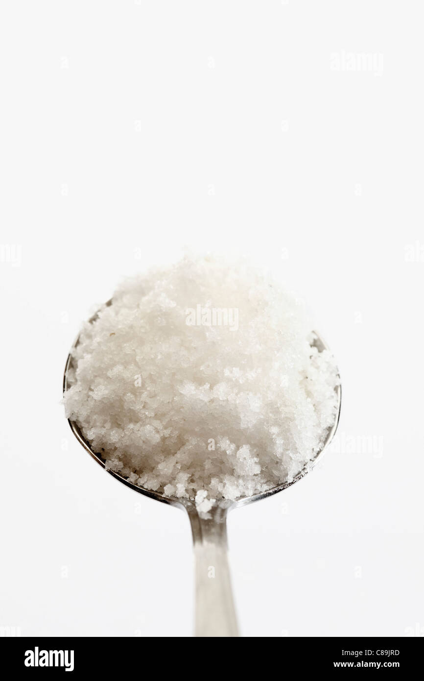 Löffel voll von Fleur de Sel vor weißem Hintergrund, in der Nähe Stockfoto