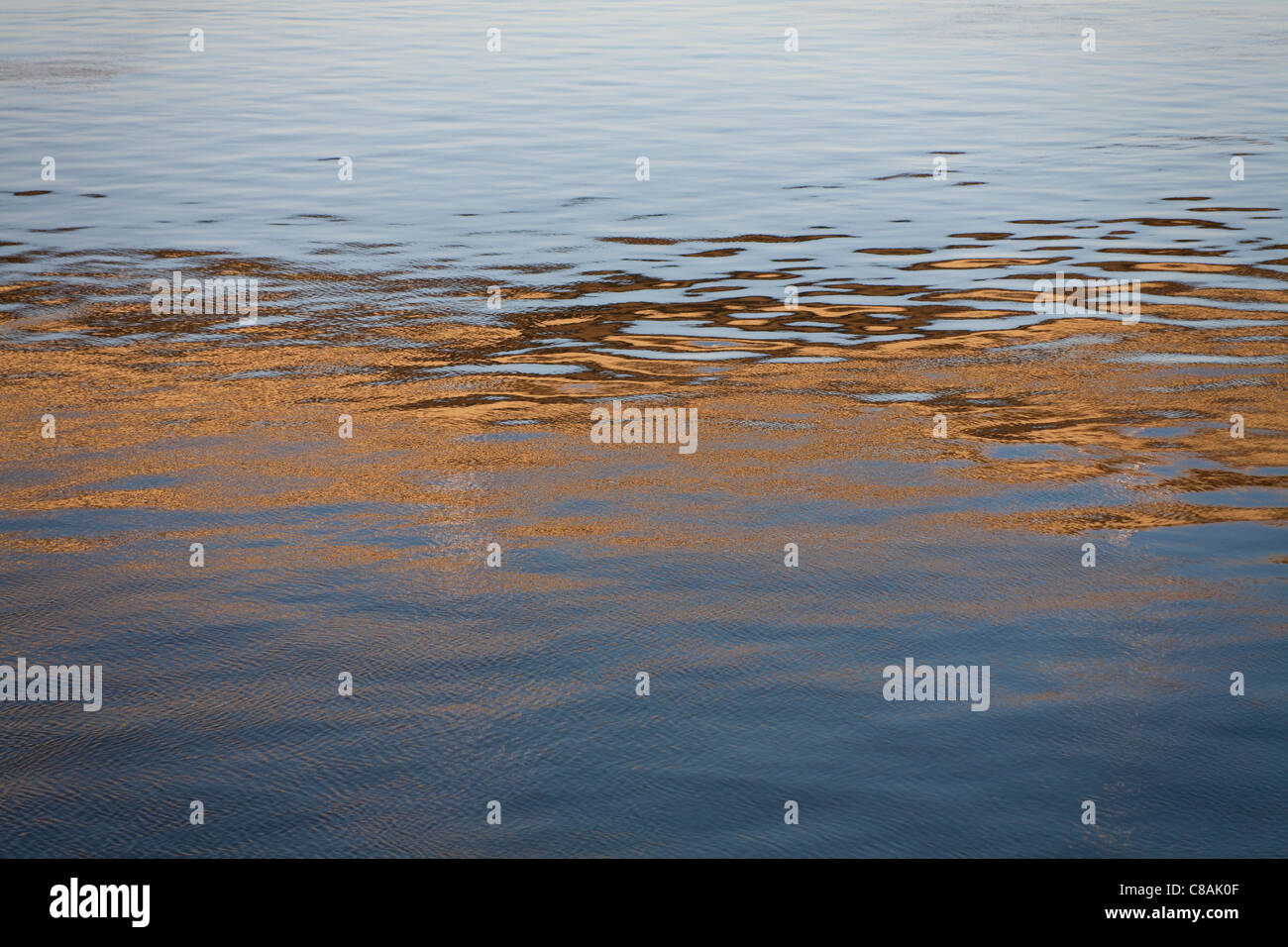 Reflexionen im beweglichen Flusswasser erstellen abstrakte Muster in braun und blues Stockfoto